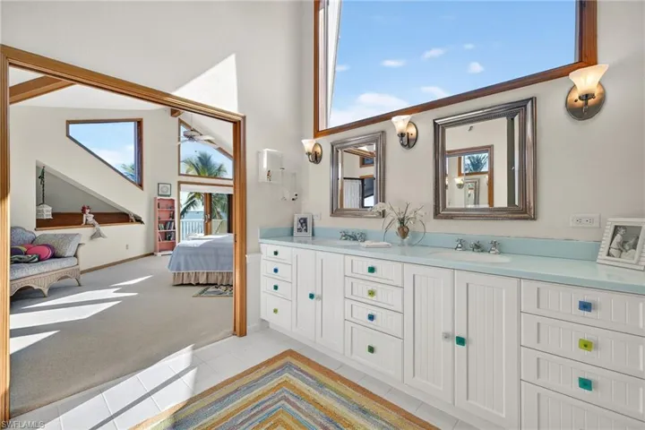 Full bathroom featuring light colored carpet, double vanity, ensuite bathroom, a high ceiling, and light tile patterned floors