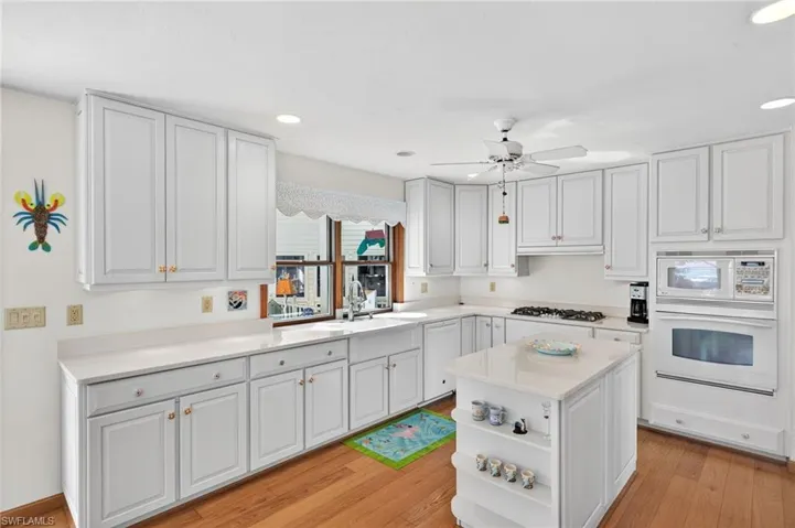 Kitchen with open shelves, white cabinetry, white appliances, a center island, and light wood finished floors