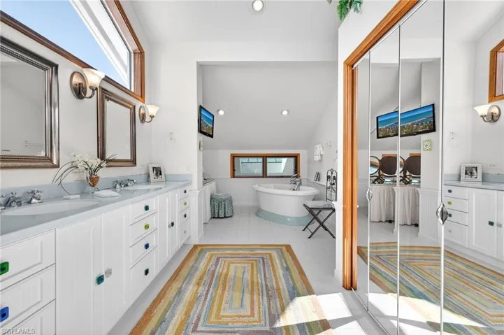 Full bathroom featuring healthy amount of natural light, recessed lighting, double vanity, vaulted ceiling, and a freestanding tub