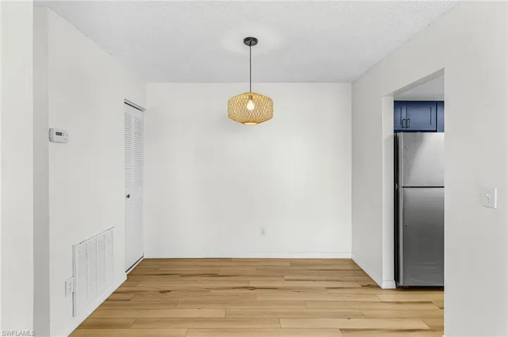 Unfurnished dining area featuring light wood-style flooring and a textured ceiling