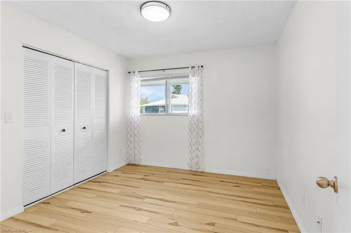 Unfurnished bedroom featuring light wood-style flooring, a textured ceiling, and a closet