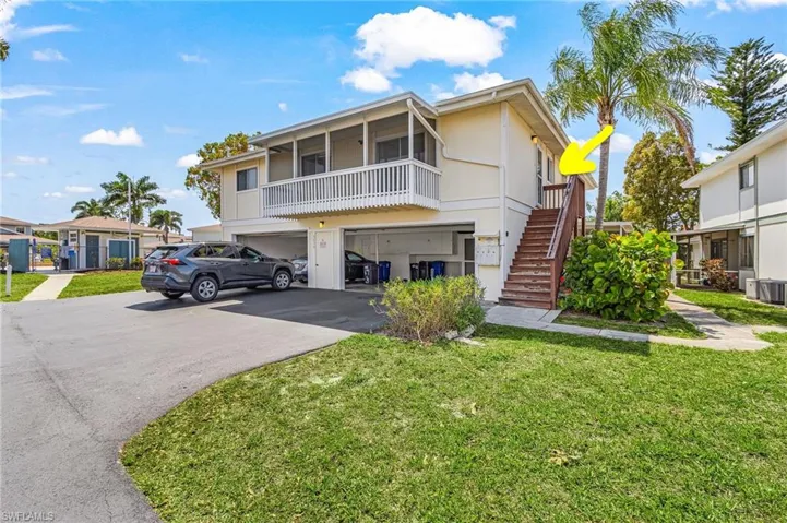 View of front of property with a front lawn, asphalt driveway, a garage, stucco siding, and a balcony