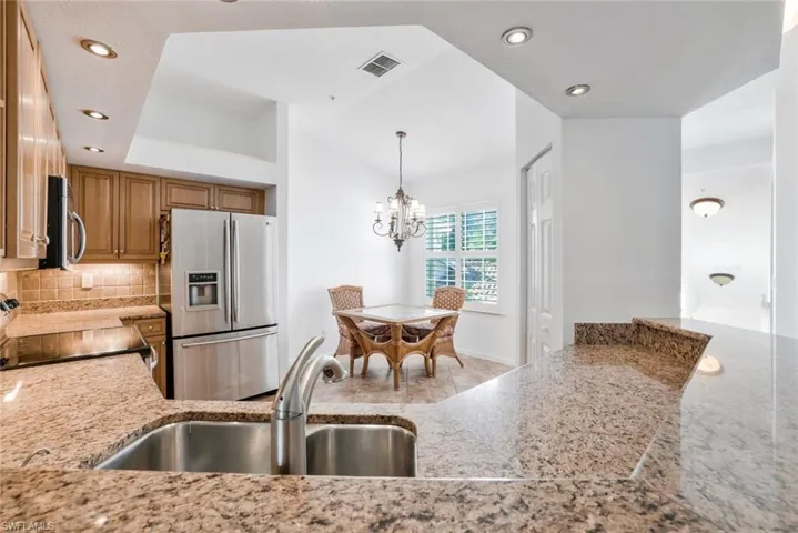 Kitchen featuring classic granite countertops, stainless steel appliances, backsplash and chandelier