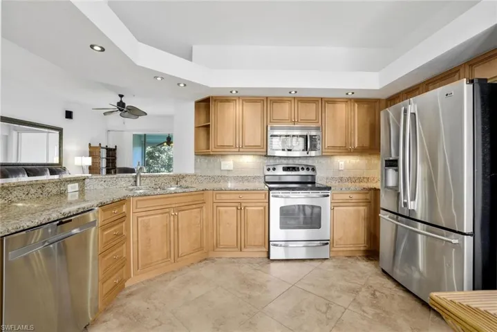 Kitchen with light tile flooring, granite counters, and stainless steel appliances