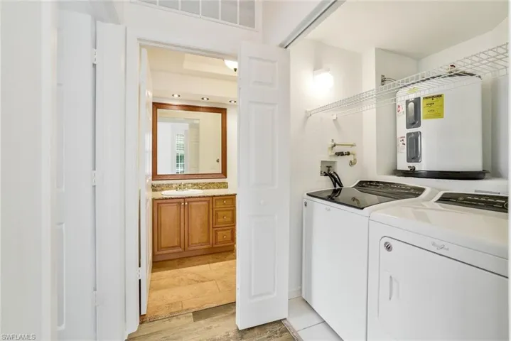 Laundry room with tile flooring, washer and dryer, and electric water heater
