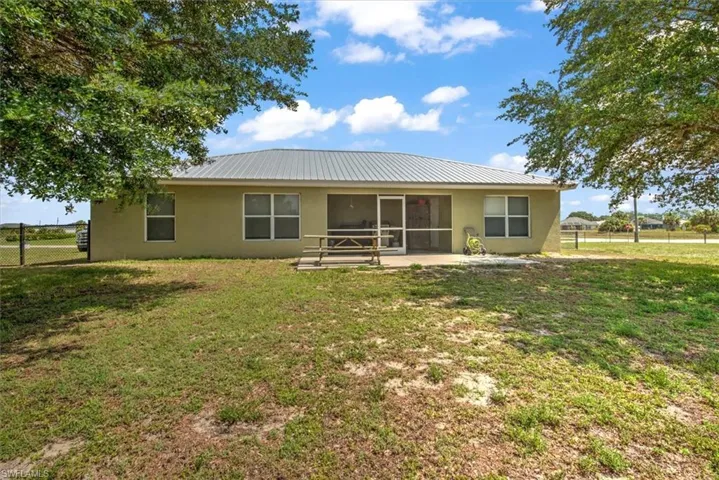 Back of property with a fenced yard and open patio.