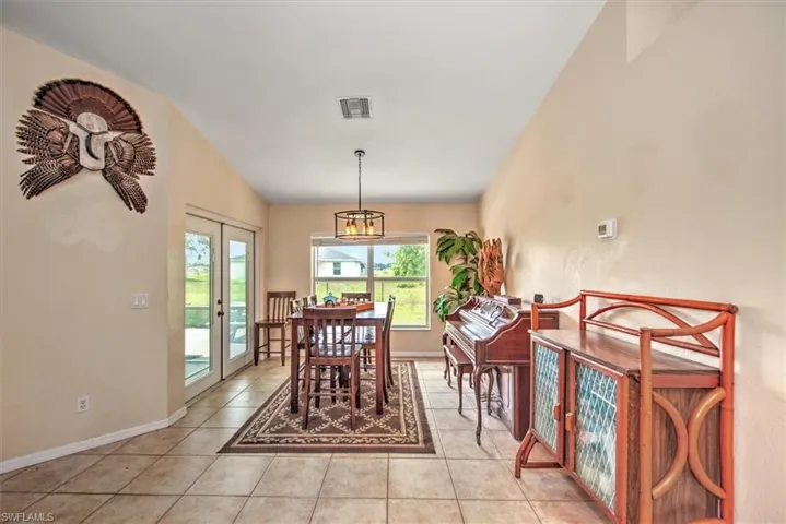 Tiled dining room featuring french doors and lofted ceiling and access to screened lanai.