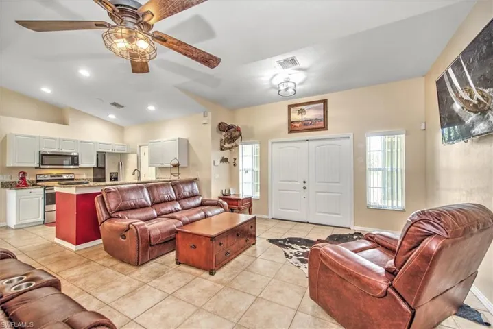Tiled living room with vaulted ceiling, double front entry doors.