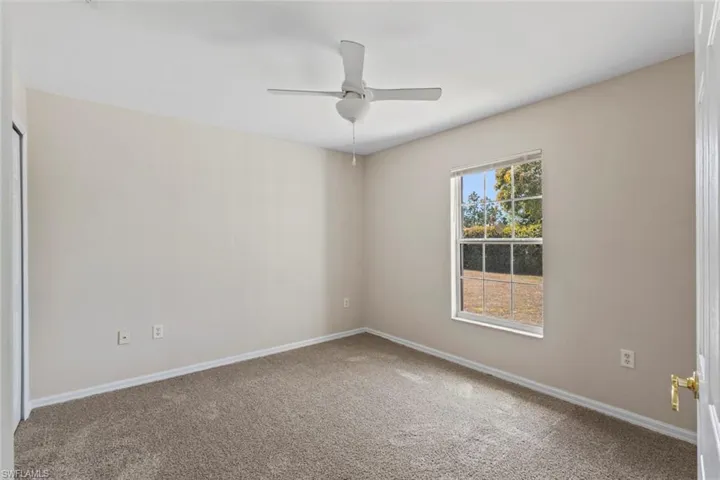 Carpeted spare room featuring baseboards and ceiling fan
