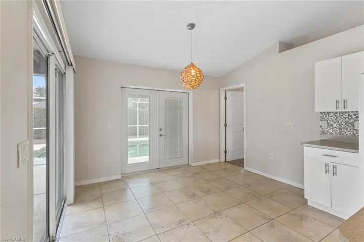 Unfurnished dining area with french doors, vaulted ceiling, and light tile patterned flooring