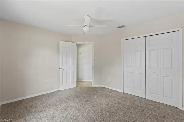 Unfurnished bedroom featuring light carpet, a closet, and ceiling fan