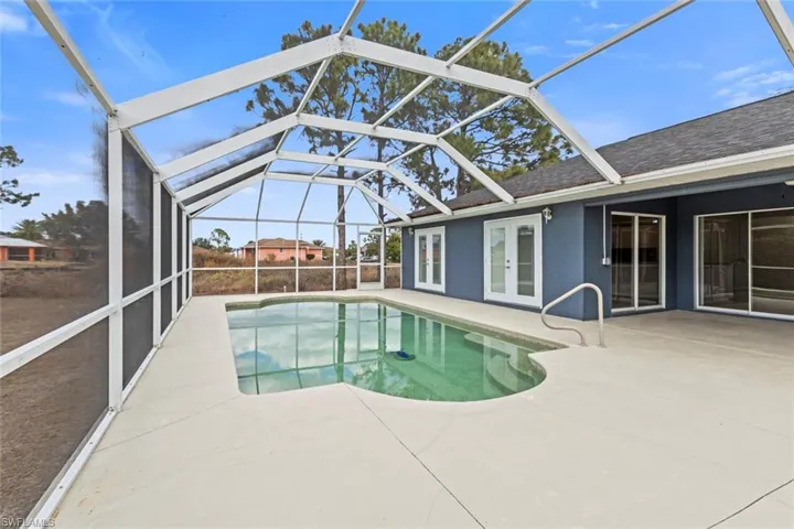 Outdoor pool featuring french doors, a sunroom, a patio, and glass enclosure