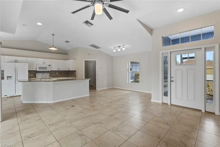 Entryway with a ceiling fan, lofted ceiling, recessed lighting, and light tile patterned floors