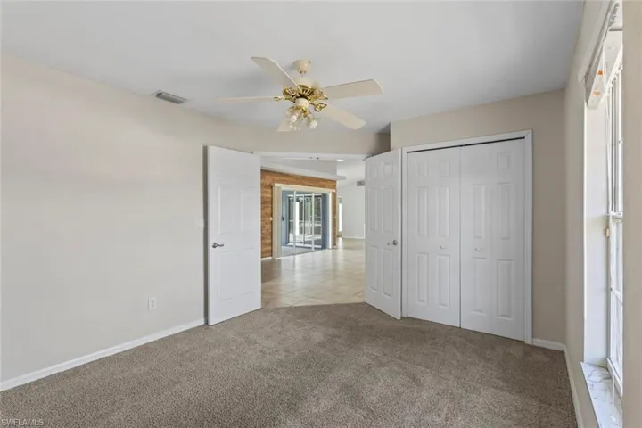 Unfurnished bedroom or office with light carpet, a closet, ceiling fan, and light tile patterned floors