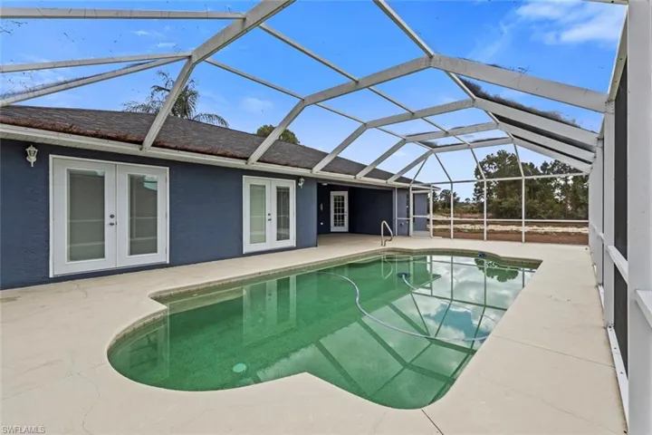 Outdoor pool with french doors, a patio, a sunroom, and glass enclosure