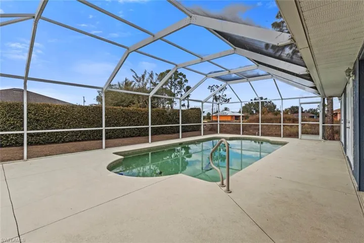 View of pool featuring glass enclosure, a sunroom, and patio surround