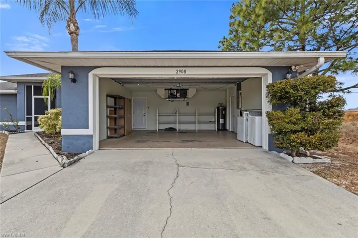 Garage featuring concrete driveway, washer and clothes dryer, and water heater