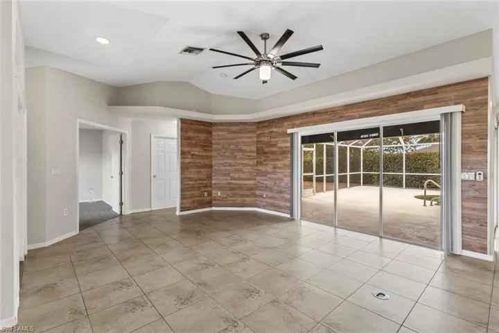 Living are with extra large ceiling fan, wooden walls, and vaulted ceiling