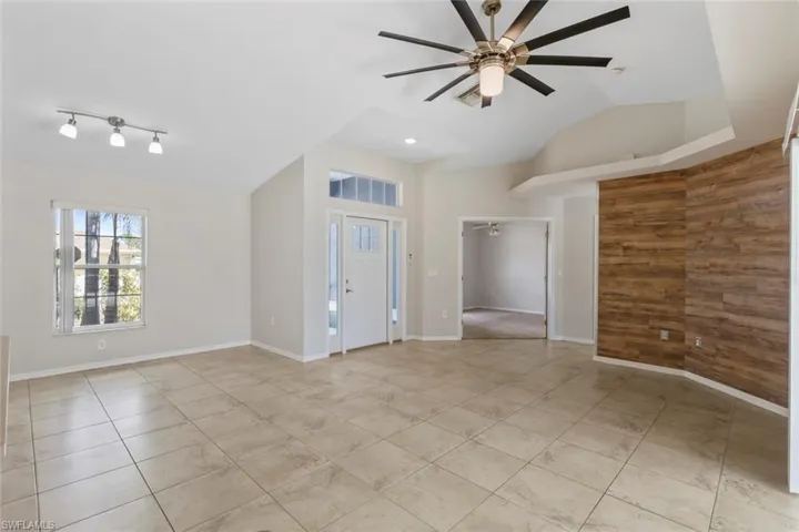 Empty room featuring ceiling fan, wooden walls, and vaulted ceiling