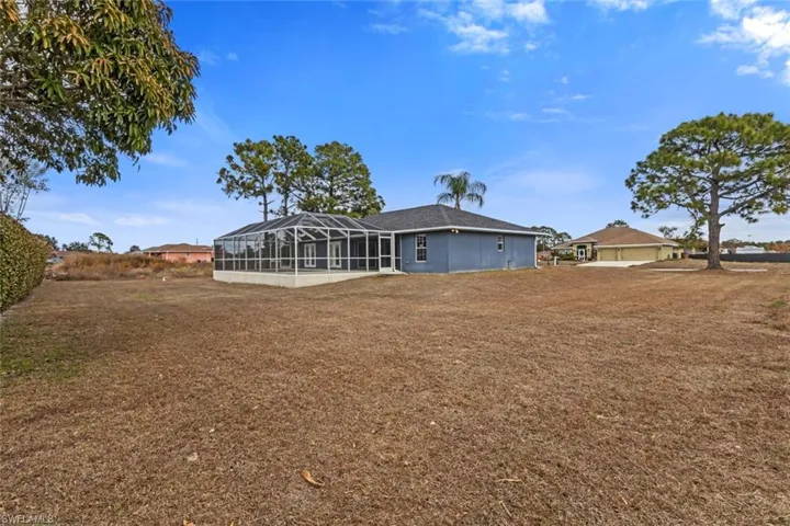 Back of house with glass enclosure, a sunroom, and a yard