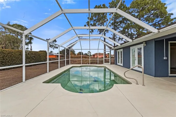 Outdoor pool featuring french doors, glass enclosure, a patio area, and a sunroom