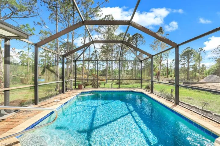 Outdoor pool featuring glass enclosure and a yard