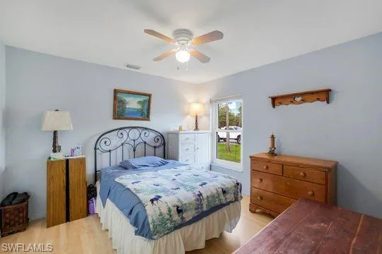 Bedroom with a ceiling fan, visible vents, and light wood finished floors