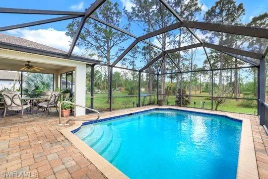 Pool featuring glass enclosure, a patio, and a ceiling fan