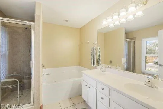 Full bath with double vanity, tile patterned flooring, a sink, and a bath