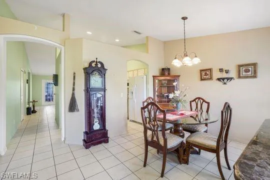 Dining area featuring arched walkways, recessed lighting, light tile patterned flooring, and an inviting chandelier