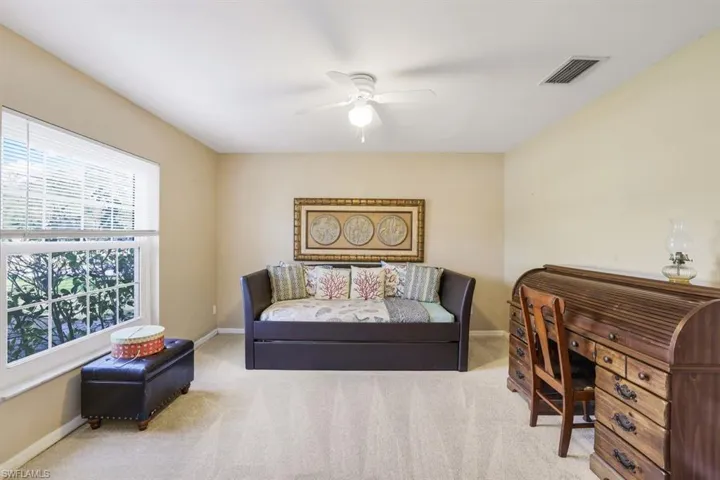 Office area featuring baseboards, visible vents, ceiling fan, and light colored carpet