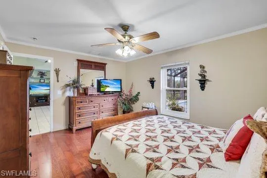 Bedroom featuring ornamental molding, ceiling fan, and wood finished floors