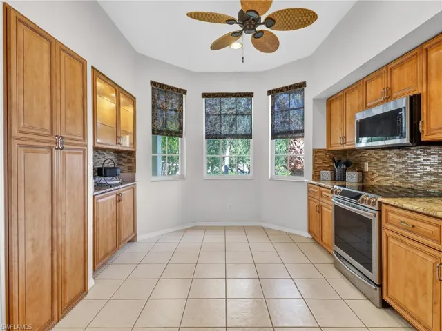 Kitchen with stainless steel appliances, tasteful backsplash, a ceiling fan, and light stone counters