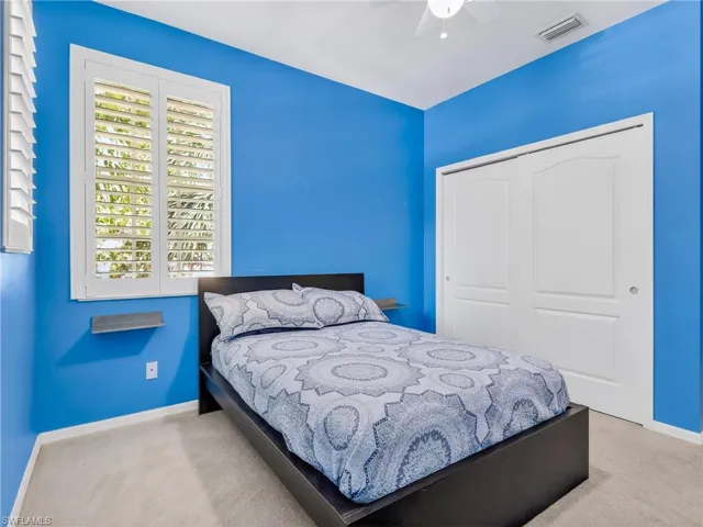 Bedroom with light carpet, a closet, and a ceiling fan