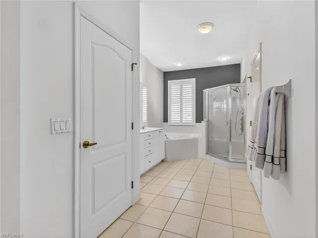 Full bathroom with a shower stall, light tile patterned floors, a garden tub, and vanity