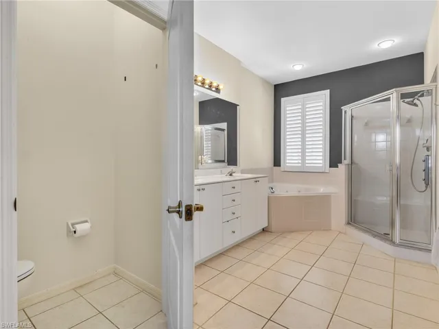 Bathroom featuring vanity, light tile patterned floors, a stall shower, and a bath