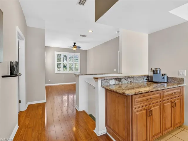 Kitchen with wood finish cabinets, light stone counters, light wood-style flooring, recessed lighting, and a ceiling fan
