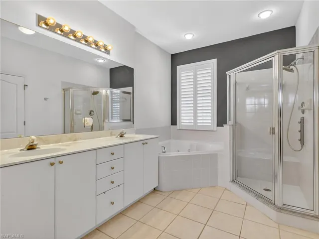 Bathroom featuring double vanity, a bath, light tile patterned flooring, and a shower stall