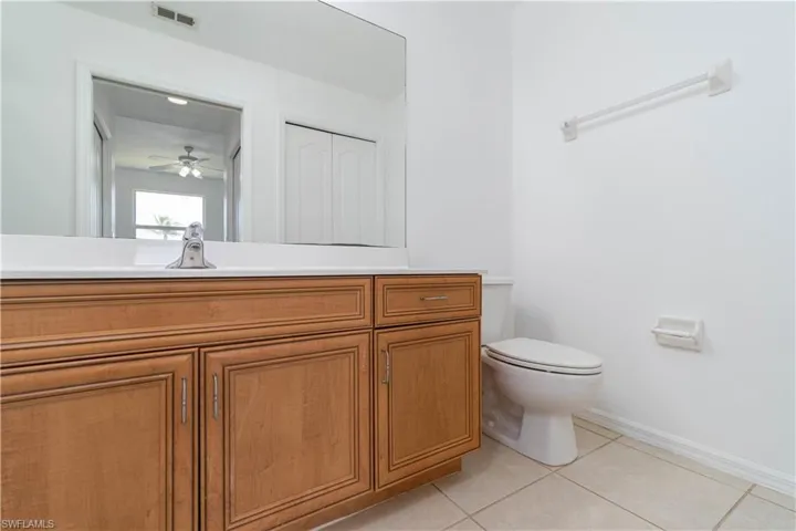 Bathroom featuring tile patterned flooring, visible vents, toilet, vanity, and ceiling fan