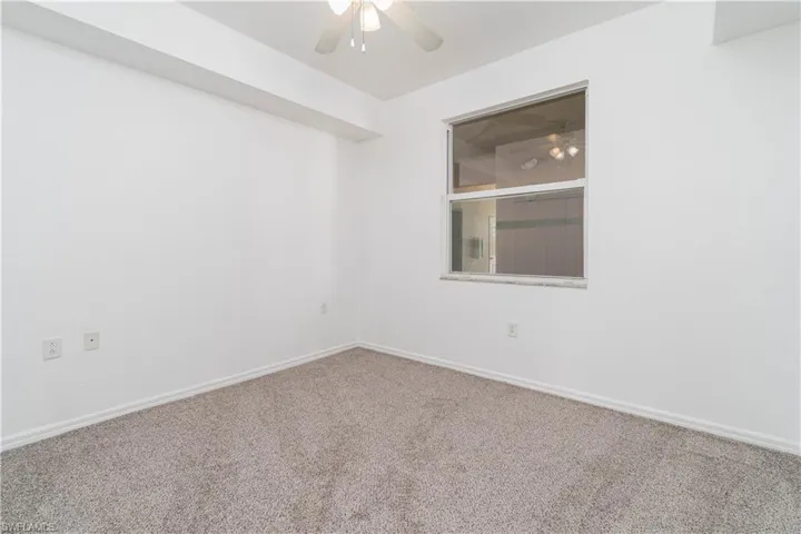 Carpeted empty room featuring baseboards and ceiling fan