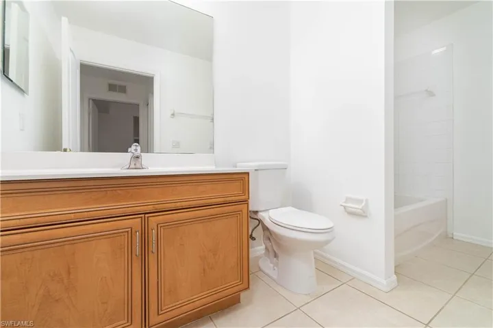 Full bath featuring toilet, baseboards, visible vents, tile patterned flooring, and vanity