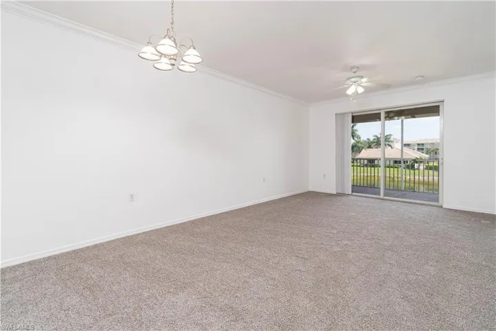 Empty room featuring baseboards, ornamental molding, carpet flooring, and ceiling fan with notable chandelier