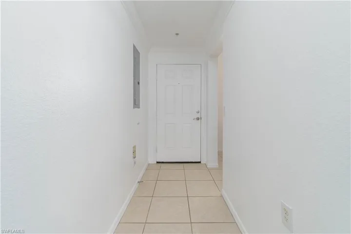 Hall featuring electric panel, baseboards, ornamental molding, and light tile patterned floors