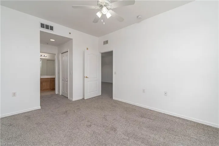 Unfurnished bedroom featuring baseboards, ensuite bathroom, visible vents, and carpet