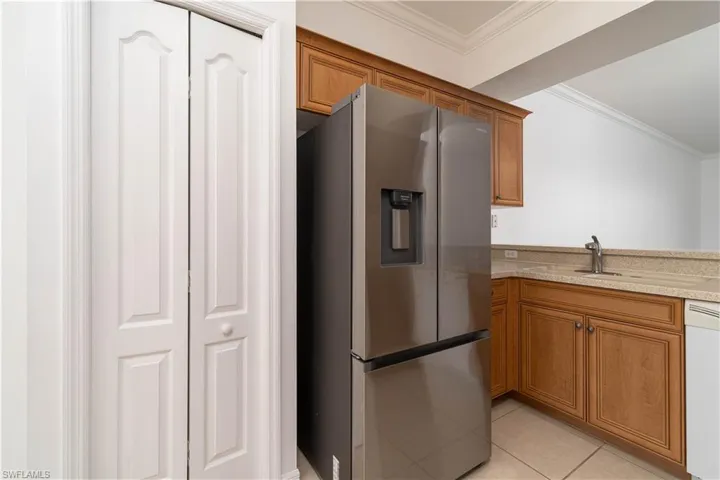 Kitchen with crown molding, white dishwasher, a sink, brown cabinetry, and stainless steel fridge with ice dispenser
