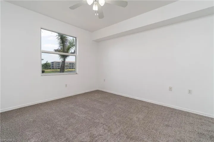 Carpeted spare room featuring baseboards and a ceiling fan