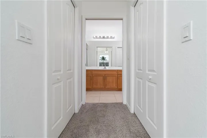 Corridor featuring light tile patterned flooring, light carpet, and a sink