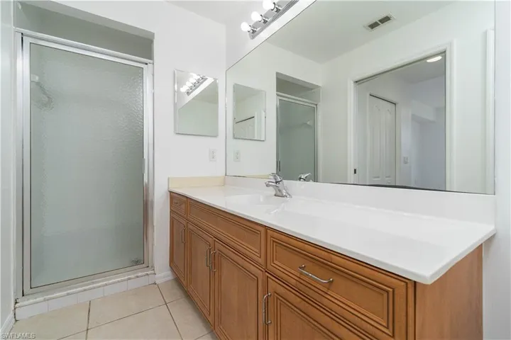 Bathroom featuring tile patterned floors, a stall shower, vanity, baseboards, and visible vents