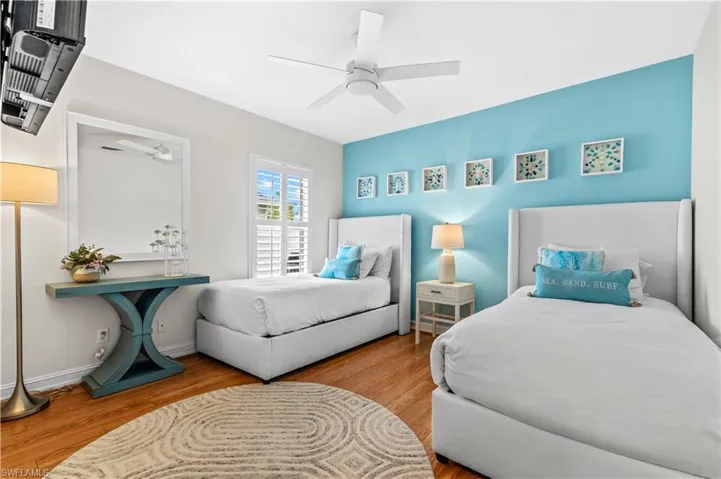 Spacious room featuring wood-finish flooring, a ceiling fan, and plantation shutters