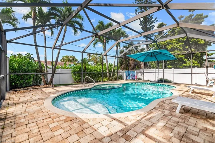 Screened enclosure featuring a freeform swimming pool and integrated spa